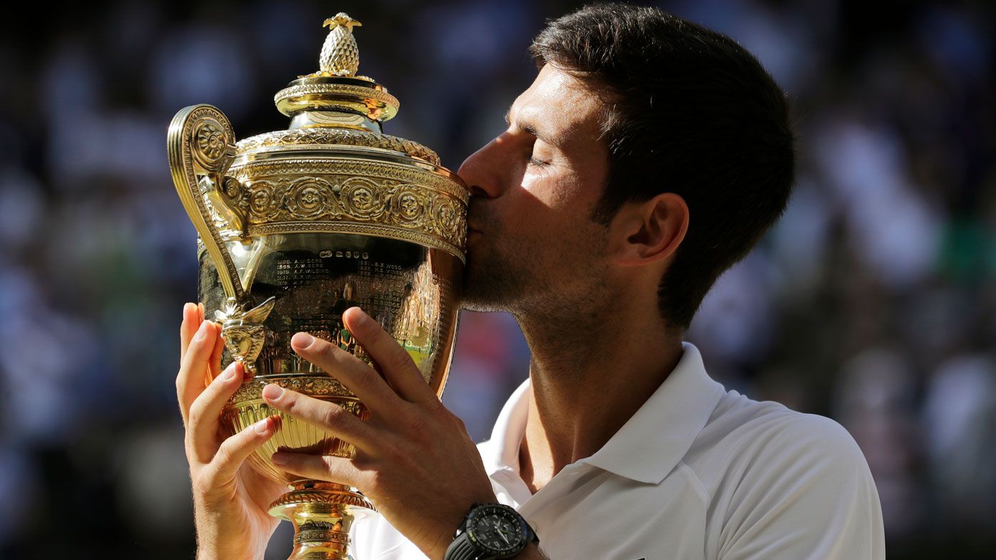 Novak Djokovic kisses the Wimbledon trophy.