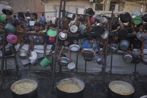 Palestinians struggle to get donated food at a community kitchen in Gaza City, northern Gaza Strip, Monday, July 14, 2025. (AP Photo/Jehad Alshrafi)