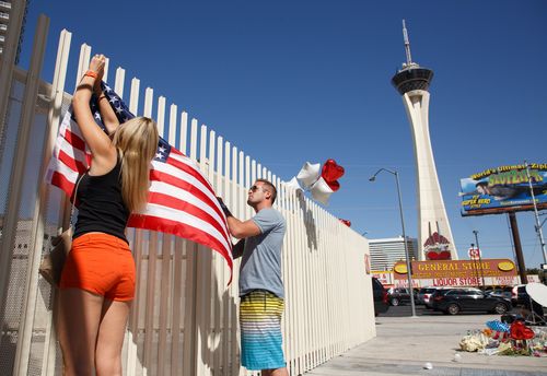 Mourners erect a US flag near the Stratosphere Tower as part of a makeshift memorial to the victims of the mass shooting in Las Vegas. (AAP)

