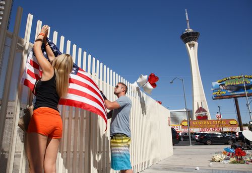 Mourners erect a US flag near the Stratosphere Tower as part of a makeshift memorial to the victims of the mass shooting in Las Vegas. (AAP)