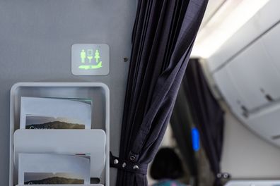 Restroom signs on the wall of the aircraft cabin that are illuminated in green indicate that it is not occupied and is available.