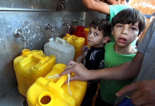Palestian children in Jabalia Refugee Camp queue for water. (Getty)