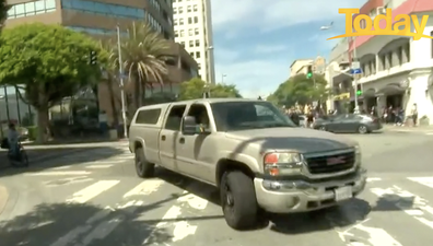 A large SUV drives by as the explosion rings out.