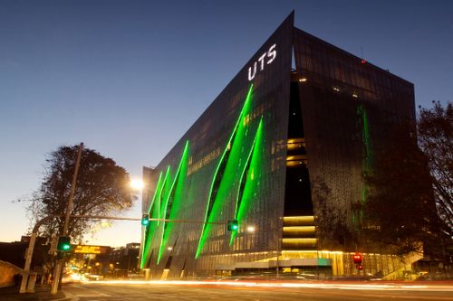 Sydney, Austrália - 8 de maio de 2014: O tráfego passa pela Universidade de Tecnologia Sydney (UTS) ao anoitecer. Na foto, está o novo edifício da Broadway/ITE, que apresenta uma fachada em forma de branqueada.