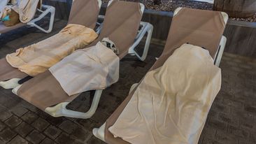 Close-up view of sun loungers with wet towels near outdoor pool in hotel. Spain.