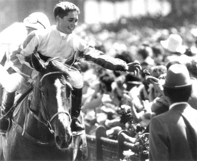 Jockey Tony Allan accepts a fitting token as he rides Empire Rose to the winner's stall