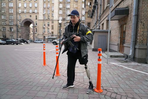 An armed civil defense man patrols an empty street due to curfew in the central o in Kyiv, Ukraine, Sunday, Feb. 27, 2022. 