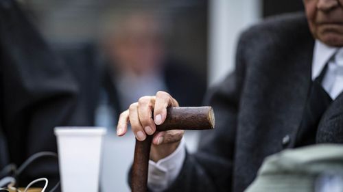 A former 94-year-old SS guard holds his walking stick at the beginning of a trial in Muenster, Germany, Tuesday, Nov.6, 2018. He is charged of accessory to murder for serving at the Nazis' Stutthof concentration camp. (Guido Kirchner/dpa via AP)