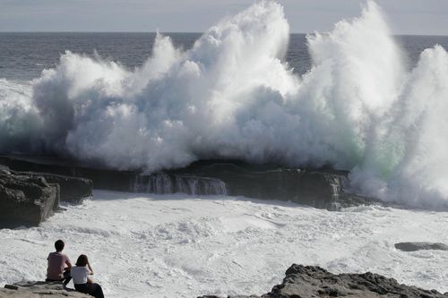 A couple watches waves hitting a coast of Shirahara town.