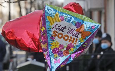 Balloons are fixed to a railing as Police officers stand outside King Edward VII's hospital in London, Tuesday, Feb. 23, 2021