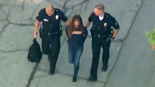 A 12-year-old girl, suspected of the US school shooting, is led away by police. (AAP)