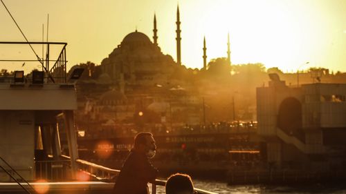 Backdropped by the Suleymaniye Mosque , a man, wearing a protective mask to help prevent the spread of the coronavirus, enjoys a boat trip over the Bosphorus Strait separating the Asian and the European sides of Istanbul, Wednesday, Oct. 21, 2020