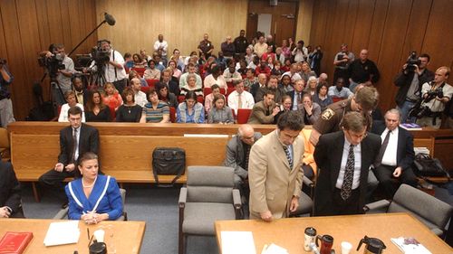 Michael Peterson, right, is handcuffed by Durham Sheriff's officer Bryan Mister after being found guilty in 2003 of first degree murder in the death of his wife, Kathleen Peterson. He was sentenced to life in prison. David Rudolf stands to the right of Mr Peterson. (AAP)