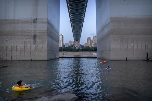 People float in the Yangtze River near bridge support columns that show previous water levels in southwestern China's Chongqing Municipality.