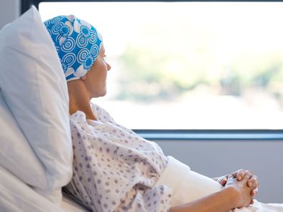 Woman with cancer wearing headscarf in hospital bed