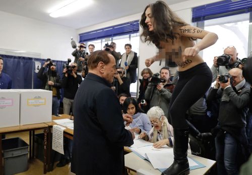 The Italian election protester had "Berlusconi, you expired" scrawled on her body, at the Milan polling station on Sunday, March 4. (AAP)