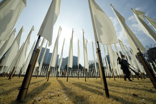 A journalist walks though 311 flags to mourn for the victims of the March 11, 2011 earthquake and tsunami during a special memorial event Friday, March 11, 2022, in Tokyo, Japan