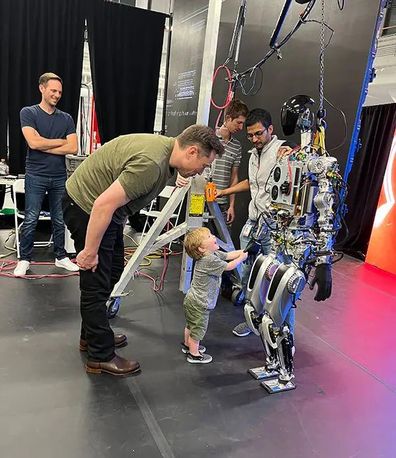 Musk hovers over daughter Exa Dark Sider?l, who goes by Y, 21 months old, as she inspects a robot.