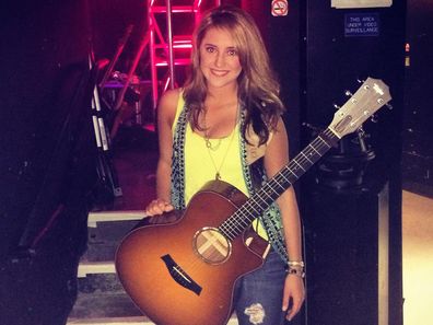 Lainey Wilson poses with her guitar in her 20s.