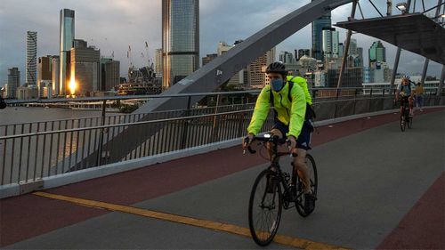 A masked cyclist travels along Southbank in Brisbane.