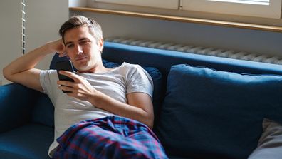 Man sitting on his lounge using his phone.