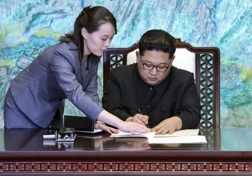 North Korean leader Kim Jong Un signs a joint declaration, with the help of his sister Kim Yo Jong (L), a senior official of the ruling Workers' Party, after talks with South Korean President Moon Jae In at the House of Peace in the border village of Panmunjeom on April 27, 2018. 
