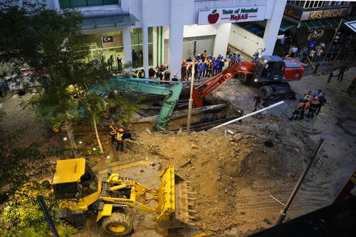 Fire and Rescue Service investigate after receiving reports that a woman fell into a sinkhole after a section of pavement collapsed in Kuala Lumpur, Friday, August 23, 2024. 