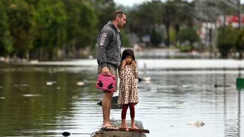 A father and his young daughter inspect a flooded street on March 31, 2022 in Lismore