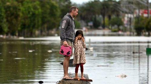 Un père et sa jeune fille inspectent une rue inondée le 31 mars 2022 à Lismore