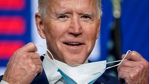 Joe Biden takes his face mask off, as he prepares to speak after the US election. 