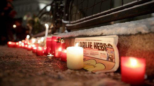 A copy of Charlie Hebdo surrounded by candles at a memorial in Vienna, Austria. (AAP)