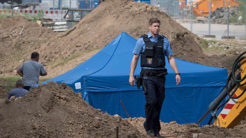 A police officer passes a blue tent that was set up over a 1.8 -ton bomb of a type dropped by British bombers during World War II in Frankfurt, Germany. (AP)