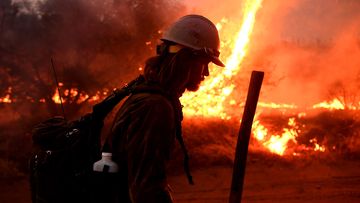 A firefighter helps to set back fires as the El dorado Fire approaches.