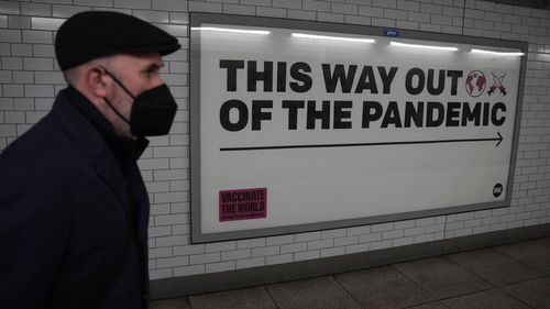 Mężczyzna nosi maskę na twarzy w tunelu prowadzącym do stacji metra Westminster w Londynie w styczniu.