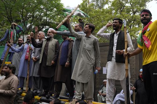 Des partisans de l'ancien Premier ministre Imran Khan se rassemblent avec des bâtons et scandent des slogans devant la résidence de Khan, à Lahore, au Pakistan, le vendredi 17 mars 2023. 