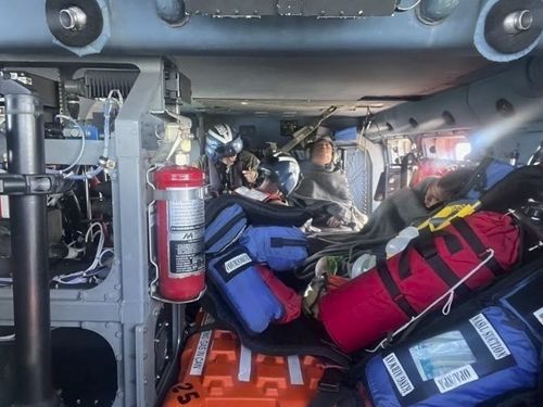 In this image provided by the U.S. Coast Guard, a Coast Guard Air Station New Orleans MH-60 Jayhawk aircrew treats three rescued boaters for injuries Sunday, Oct. 9, 2022, approximately 25 miles offshore from Empire, La. Three men whose fishing boat sank in the Gulf of Mexico off the Louisiana coast were rescued after surviving for more than a day despite being attacked by sharks that inflicted deep cuts on their hands and shredded one of their life jackets, according to their rescuers. 