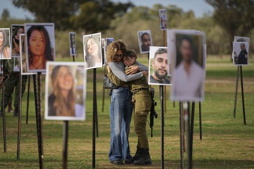 Israelis embrace next to photos of people killed and taken captive by Hamas militants