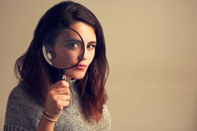 young woman looking through a magnifying glass