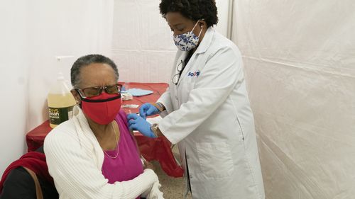 Dr, Jacqueline Delmont, Chief Medical Officer at Somos, gives Helen Washington, 76, the first dose of the coronavirus vaccine in the Bronx borough of New York.