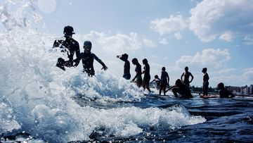 Teenagers enter the water on North Bondi Rocks at the start of the summer school holidays