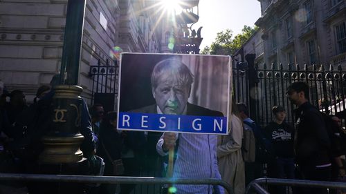 Un protestatar ține un banner care îl înfățișează pe premierul britanic Boris Johnson, după ce un raport de investigație l-a acuzat pe Johnson și pe alți lideri de top că au permis partidelor guvernamentale să fi încălcat regulile de blocare a COVID-19 din Marea Britanie. 