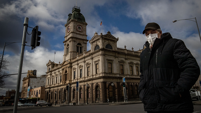 A man wearing a mask walks across Sturt Street in Ballarat on August 21, 2020 in Ballarat, Australia. 