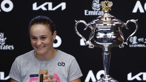 Ash Barty of Australia drinks a glass of champagne at a press conference after defeating Danielle Collins