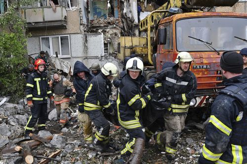 Salvatorii transportă cadavrul unui civil pe locul unui bloc de apartamente distrus de bombardamentele rusești în Bakhmut, regiunea Donețk, Ucraina.