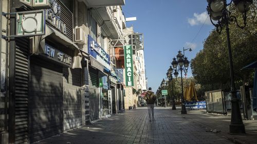 FIȘAR - Un bărbat trece pe lângă magazine închise de pe celebrul Bulevar Habib Bourguiba din Tunis, unde au izbucnit proteste în masă în 2011, cea de-a 10-a aniversare a revoltei, în timpul unui blocaj național ca urmare a unei creșteri a cazurilor de COVID-19, în Tunis, joi.  , 14 ianuarie 2021. În ciuda dezastrului electoral, președintele din ce în ce mai autoritar al Tunisiei pare hotărât să răstoarne sistemul politic al țării, amenințând să demonteze fragila democrație și să prăbușească economia țării nord-africane.