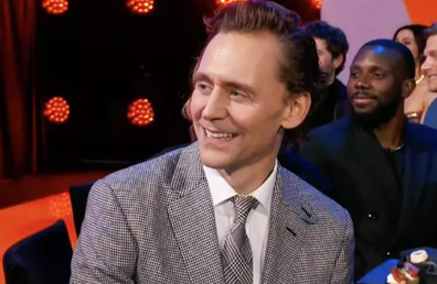 Tom Hiddleston laughing at a joke about Taylor Swift dominating pop culture. 