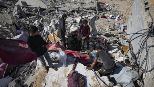 Members of the Abu Al Zamar family salvage items from under the rubble of their destroyed family home, in Rafah, southern Gaza Strip, Tuesday, Jan. 21, 2025, days after the ceasefire deal between Israel and Hamas came into effect. (AP Photo/Abdel Kareem Hana)