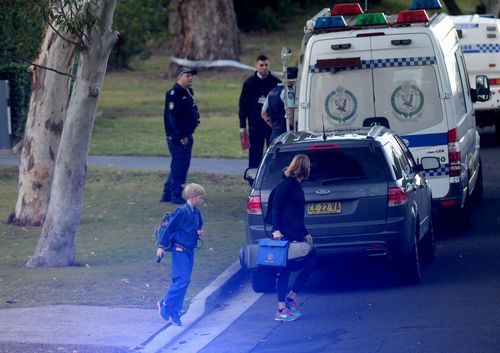 Parents get their children ready for school as police continue to scour the area. Picture: AAP