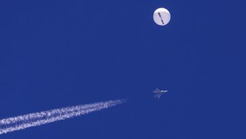 In this photo provided by Chad Fish, a large balloon drifts above the Atlantic Ocean, just off the coast of South Carolina, with a fighter jet and its contrail seen below it.
