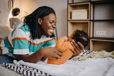 Shot of a young woman playing with her adorable baby  on the bed at home